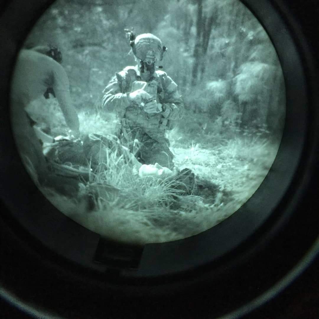 A night vision picture of Army Ranger and Drexel University's College of Nursing and Health Professions Health Sciences student Nicholas Eltman performing medical procedures a simulation exercise in darkness. 